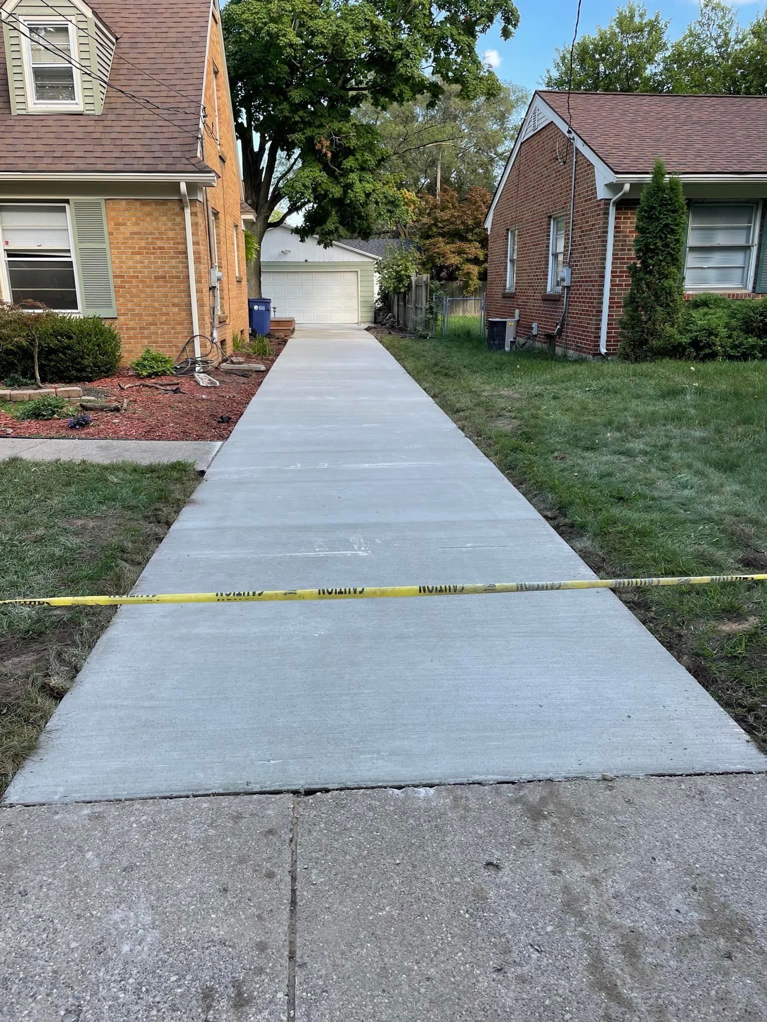 A concrete walkway leading to a brick house.