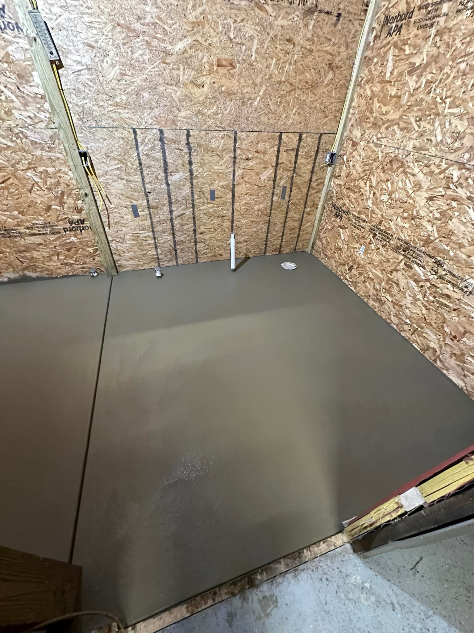 A room with a concrete floor and a wooden wall.