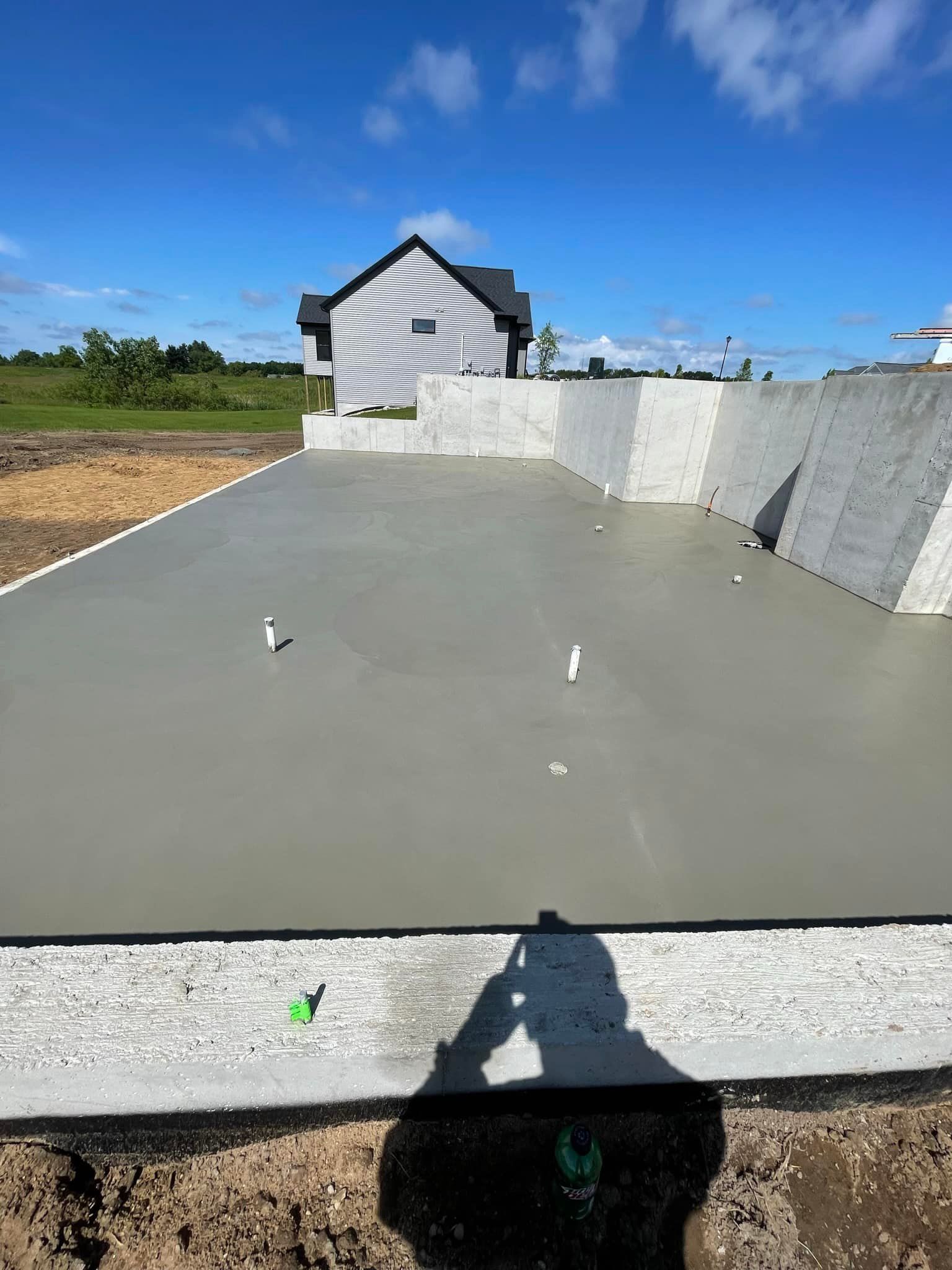 A shadow of a person is cast on a concrete surface in front of a house.