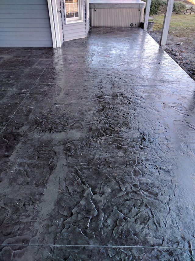 A concrete patio with a hot tub in the background.