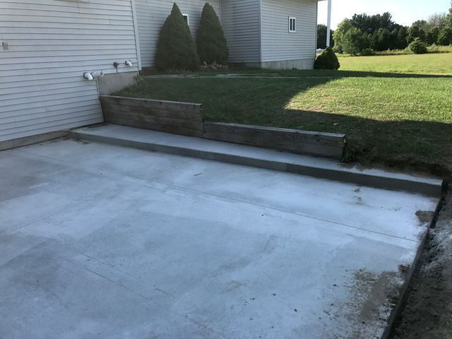 A concrete driveway is being built in front of a house.