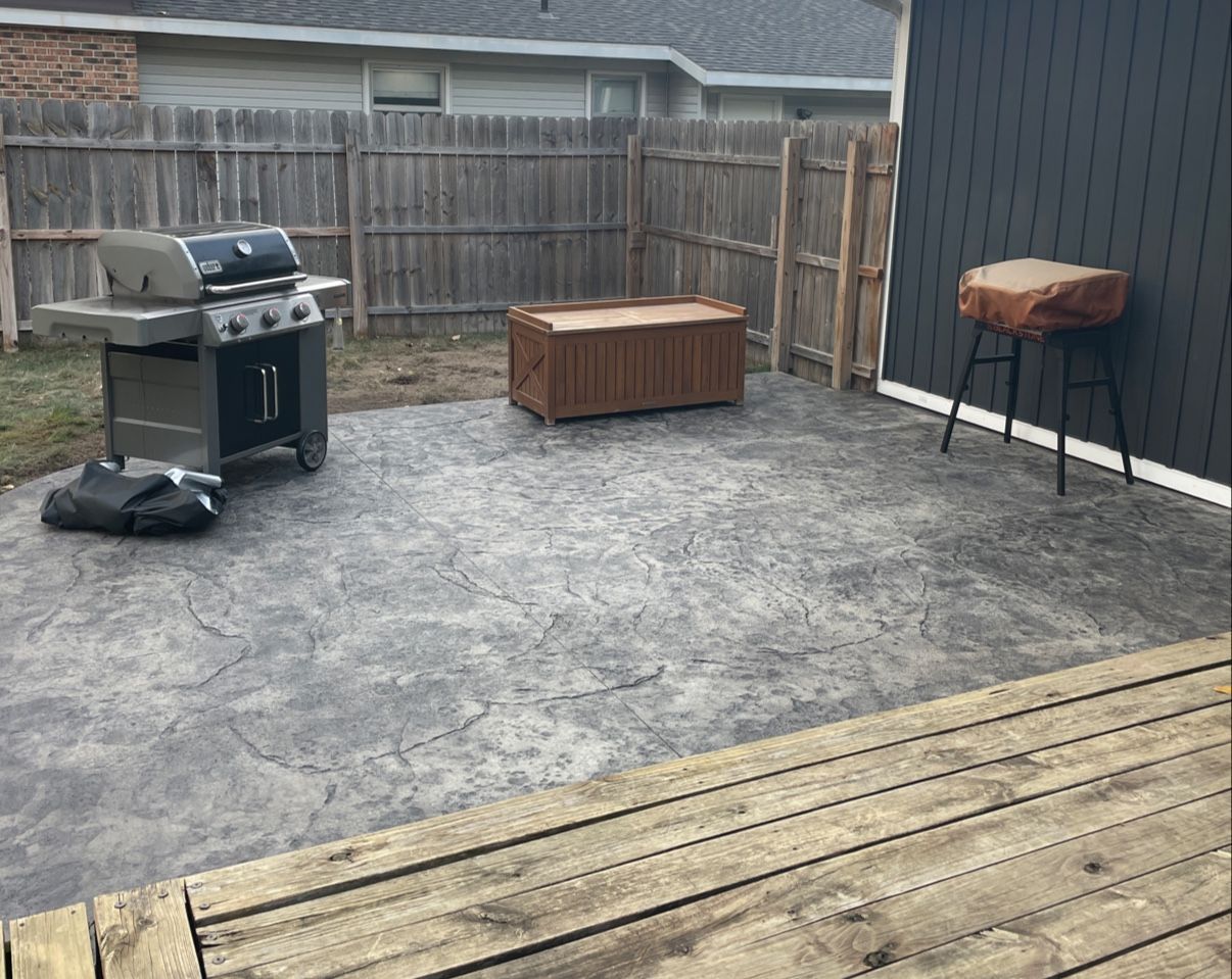 A grill is sitting on a patio next to a wooden deck.