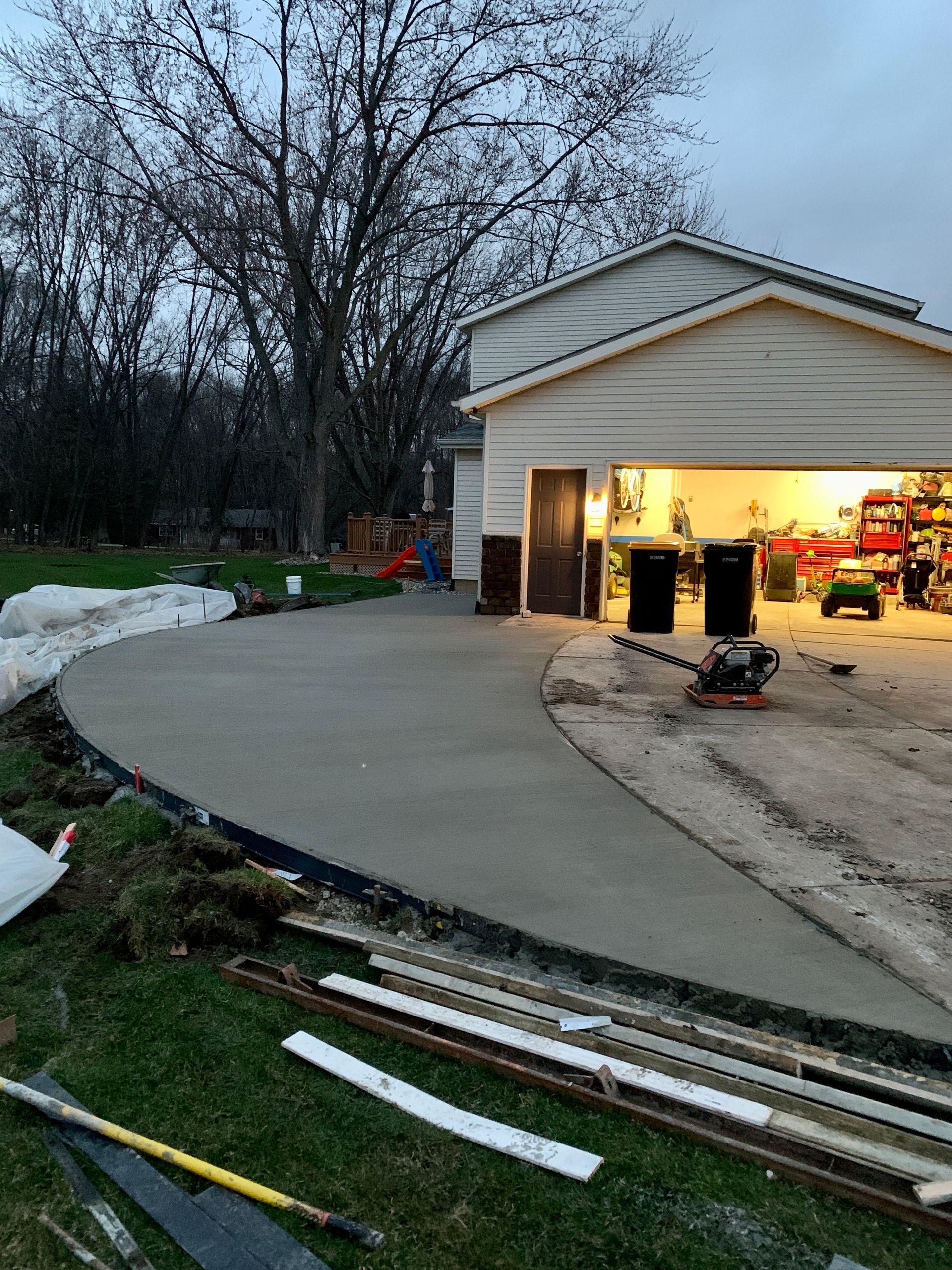 A concrete driveway is being built in front of a garage.