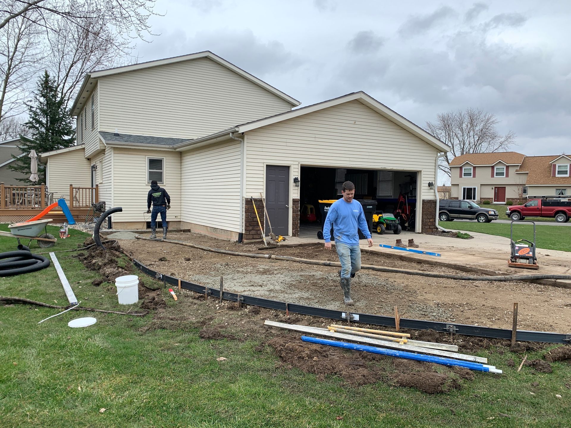 A man in a blue shirt is standing in front of a house.