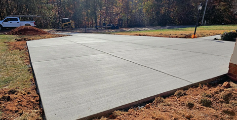 A white truck is parked on the side of a concrete driveway.