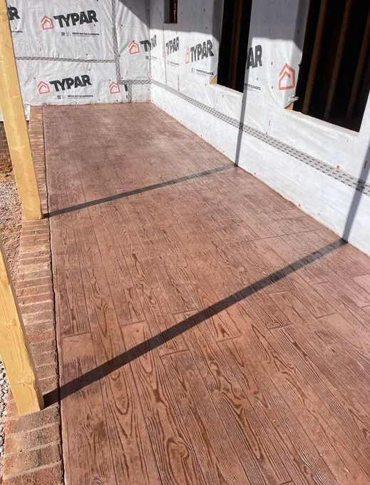 A patio with a wooden floor and a brick wall.