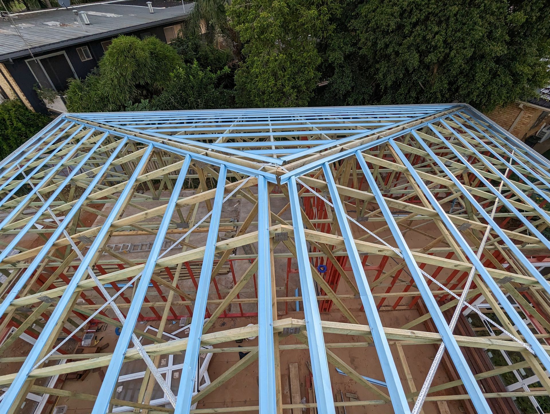 Wooden Roof Frame Construction Against a Backdrop of Green Trees and Blue Sky — CJ Custom Carpentry in Port Macquarie, NSW