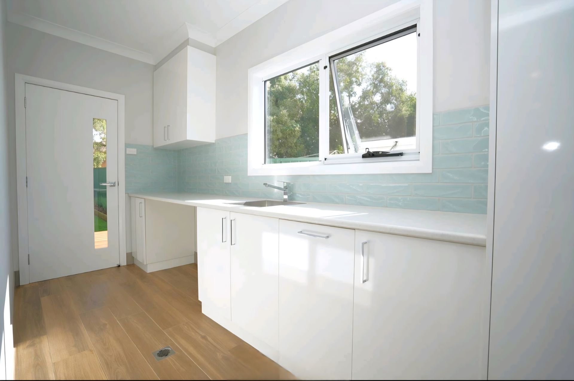 Laundry Room With Washer, Dryer, Cabinets, Sink, Door, and a Wicker Hamper — CJ Custom Carpentry in Port Macquarie, NSW
