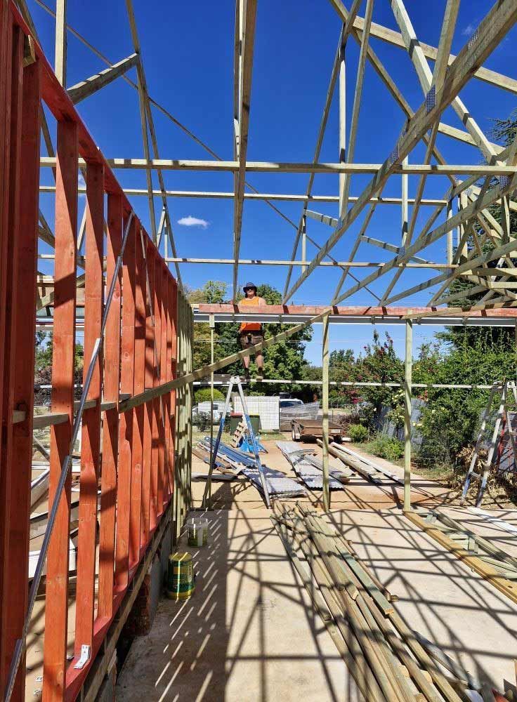 Construction Site With Wooden Framing and Roof Beams Against a Blue Sky — CJ Custom Carpentry in Port Macquarie, NSW
