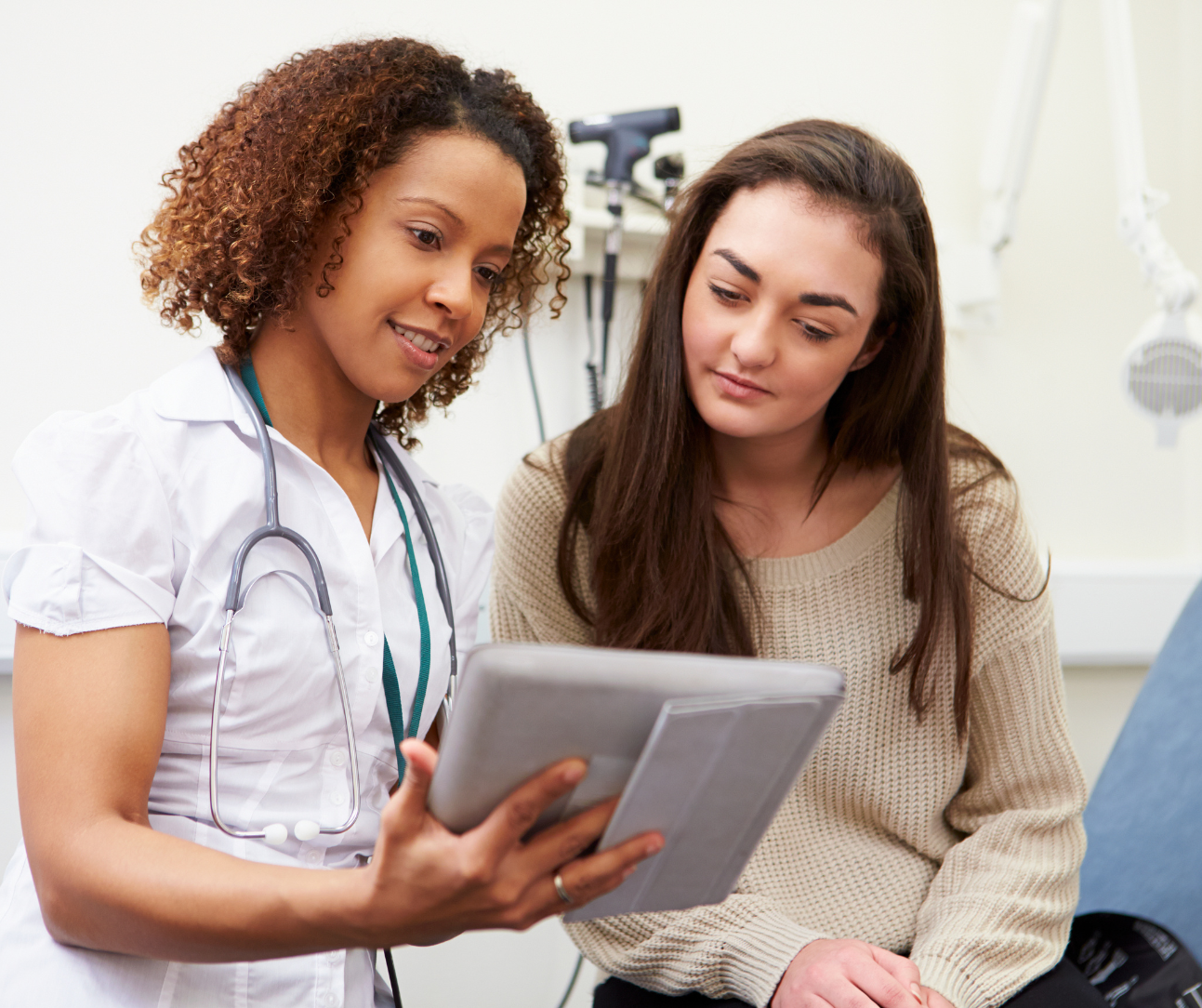 a health and wellness practitioner wearing a stethoscope and showing something to a patient