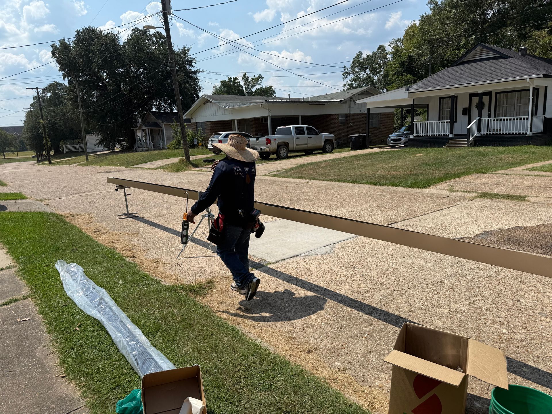 Two-story house with screened-in porch. Light siding, dark roof, blue sky, trees in background.