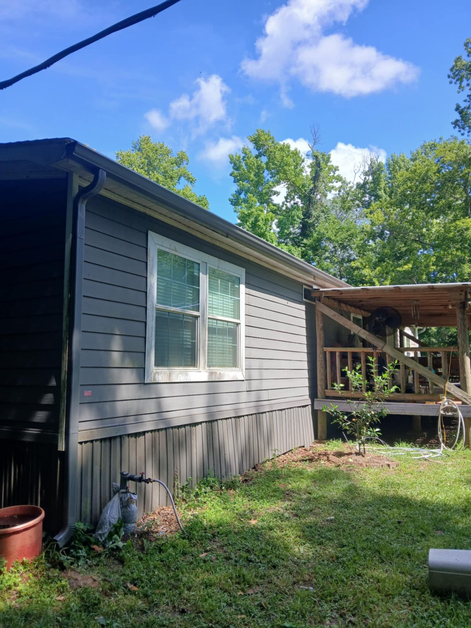 Gray house with white window and small porch under a blue sky.