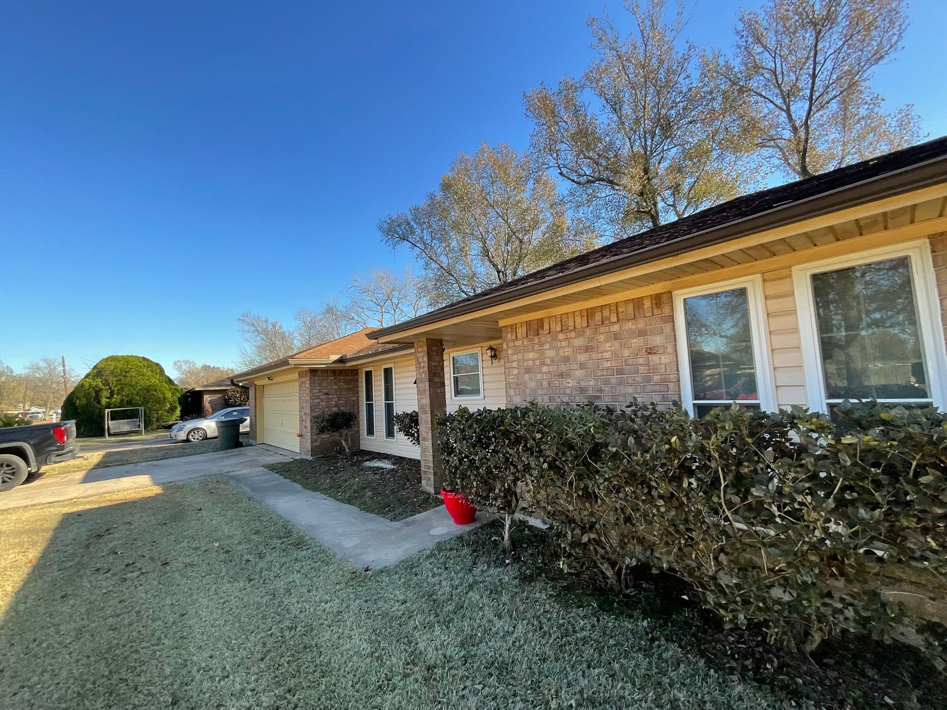 A row of brick and beige houses under a blue sky, with garages and a front lawn.