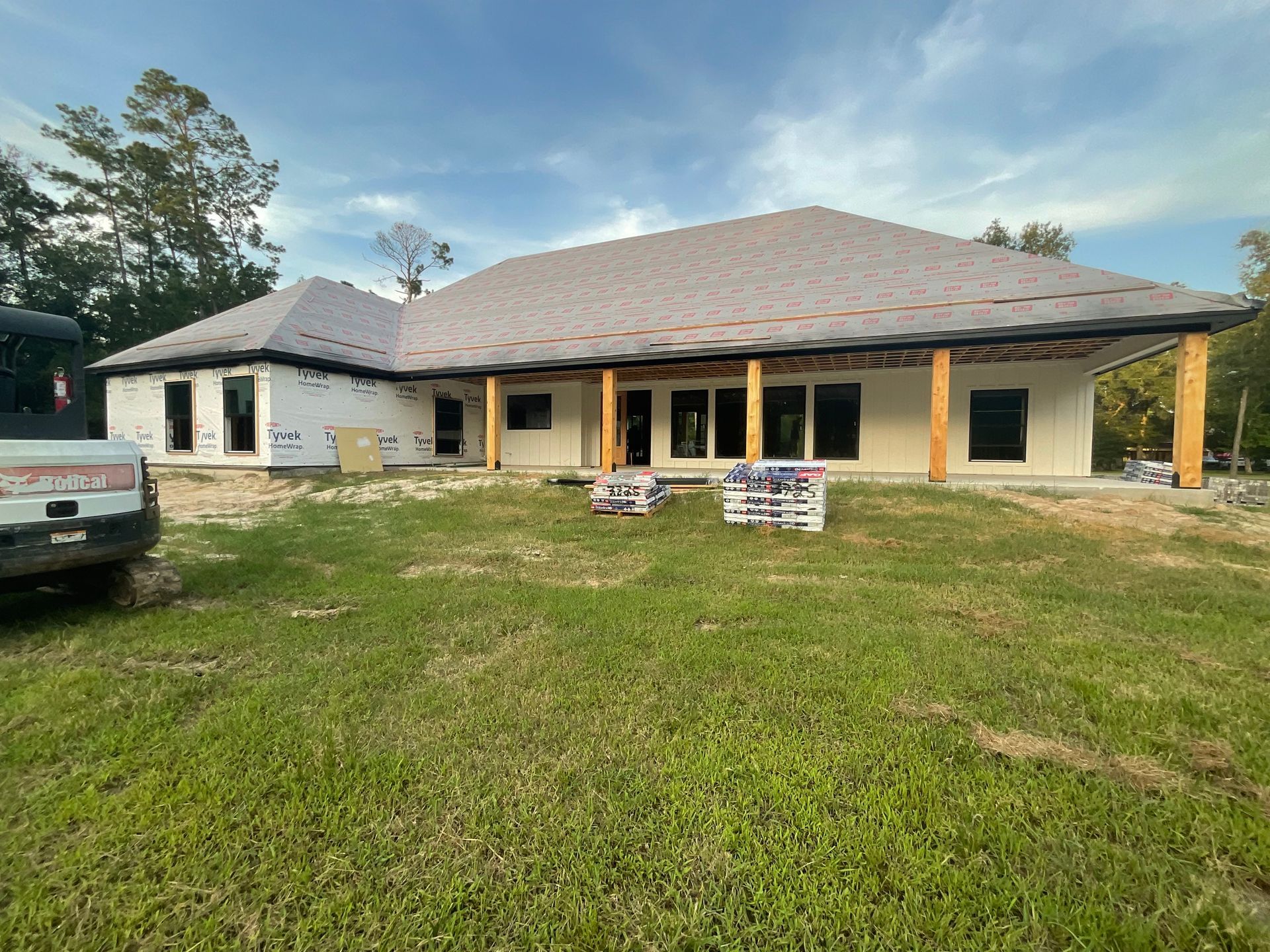 House under construction with a gray roof and white siding, on a grassy lot.
