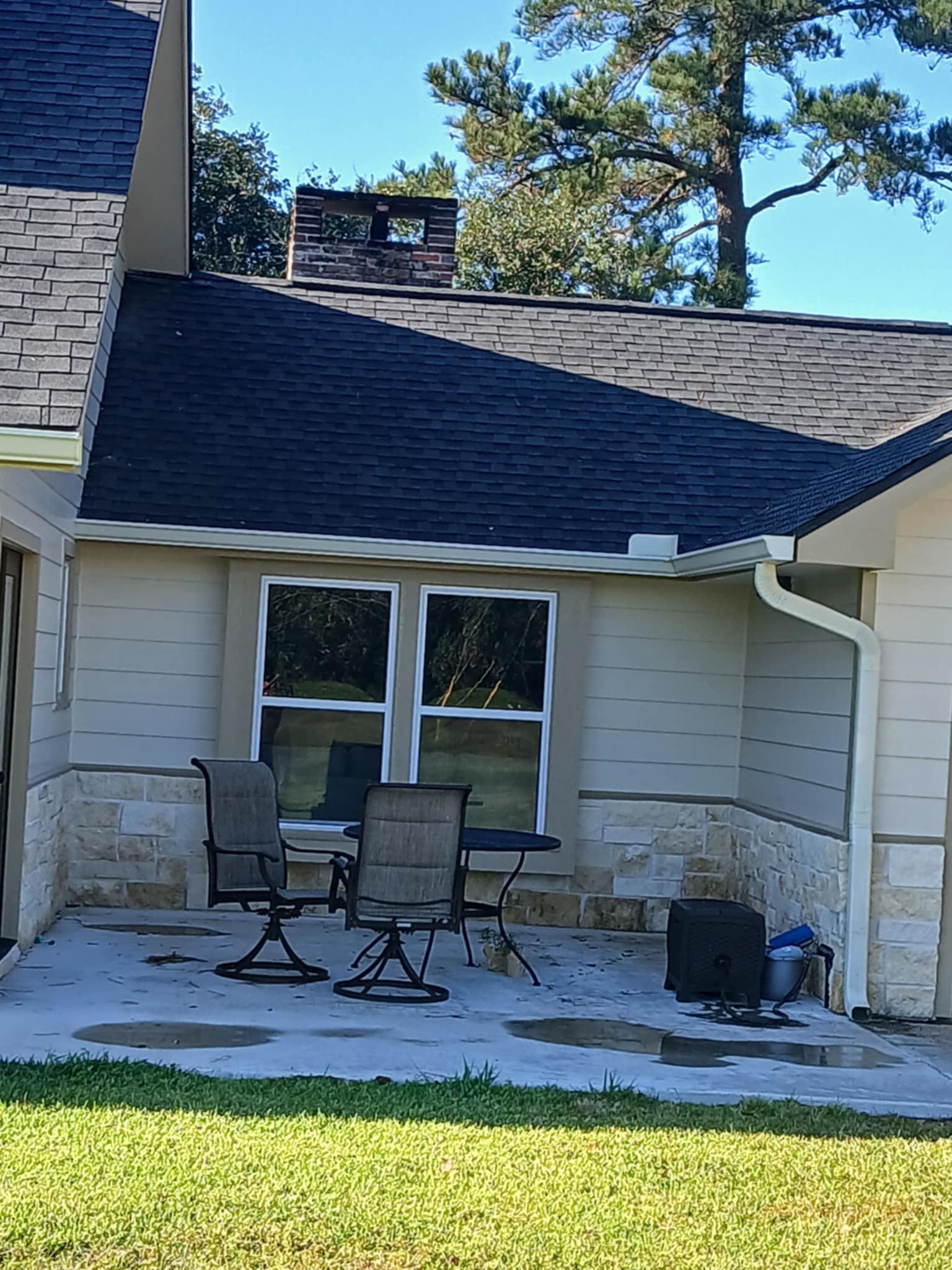 Backyard patio with chairs, windows, and roof against blue sky.