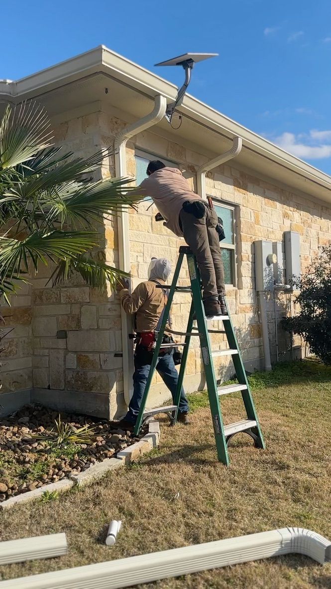 Aerial view of a brown shingled roof with a light stone exterior and surrounding greenery.