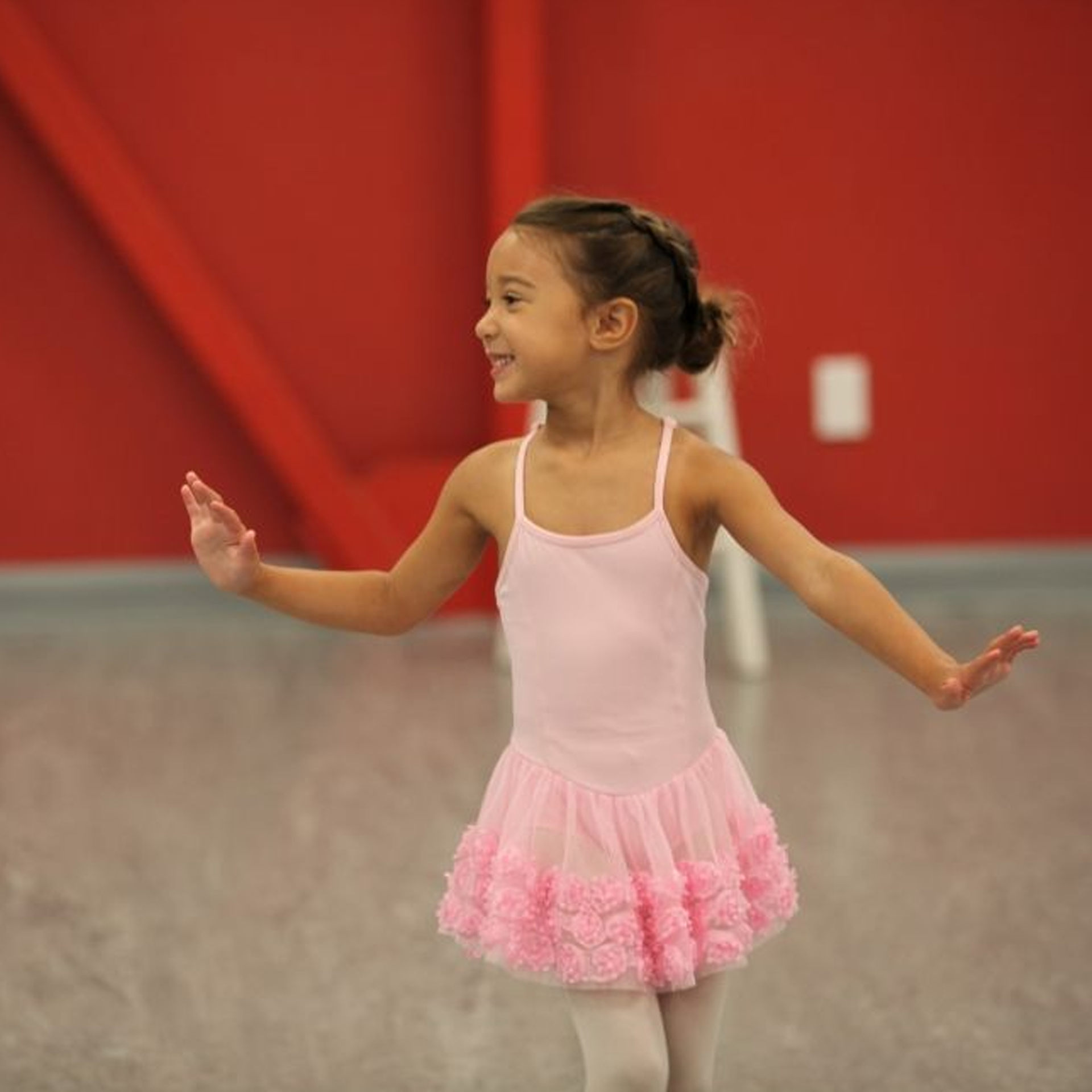 A little girl in a pink dress is dancing