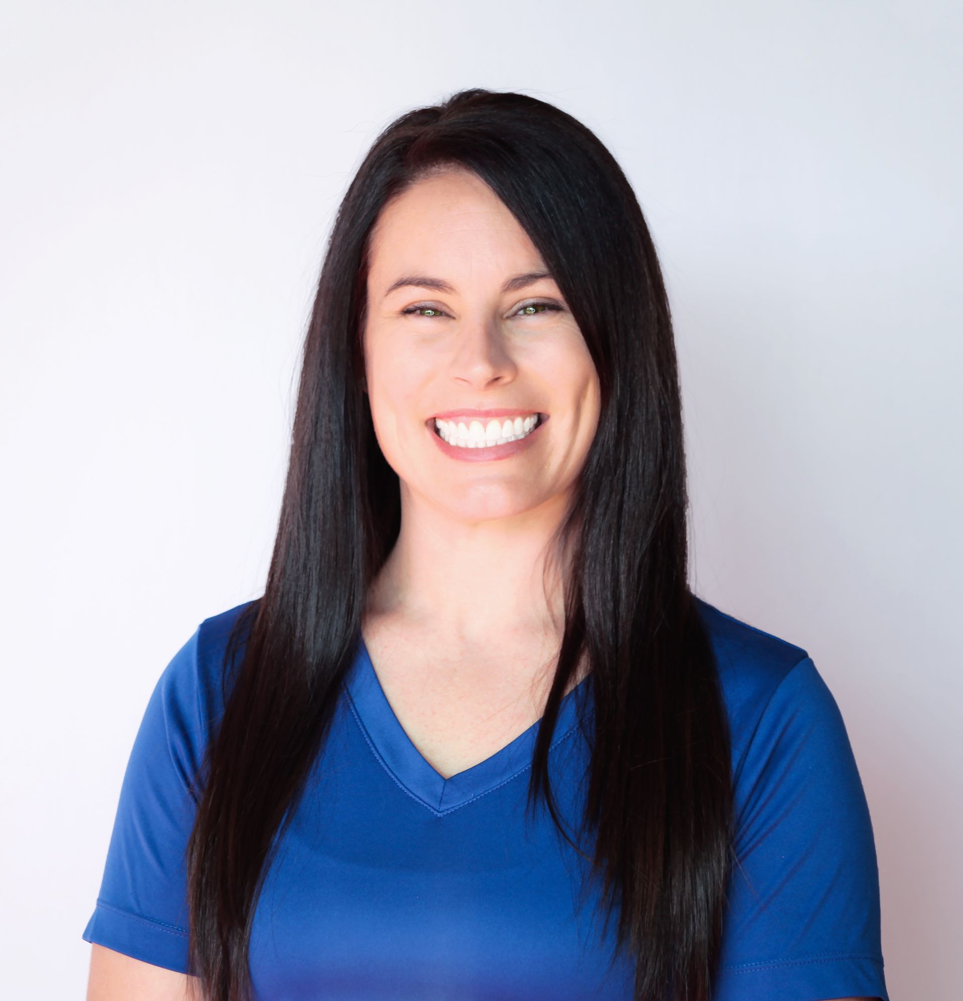 A woman in a blue shirt is smiling for the camera