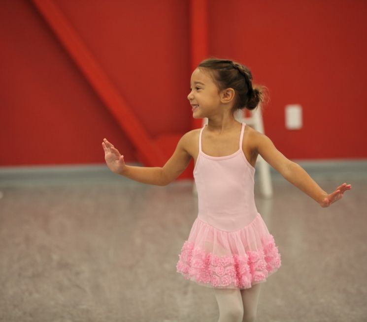 A little girl in a pink dress is dancing