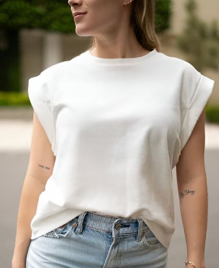Una mujer lleva una camisa blanca y jeans azules.