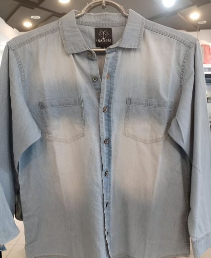 Una camisa vaquera azul claro está colgada en una percha