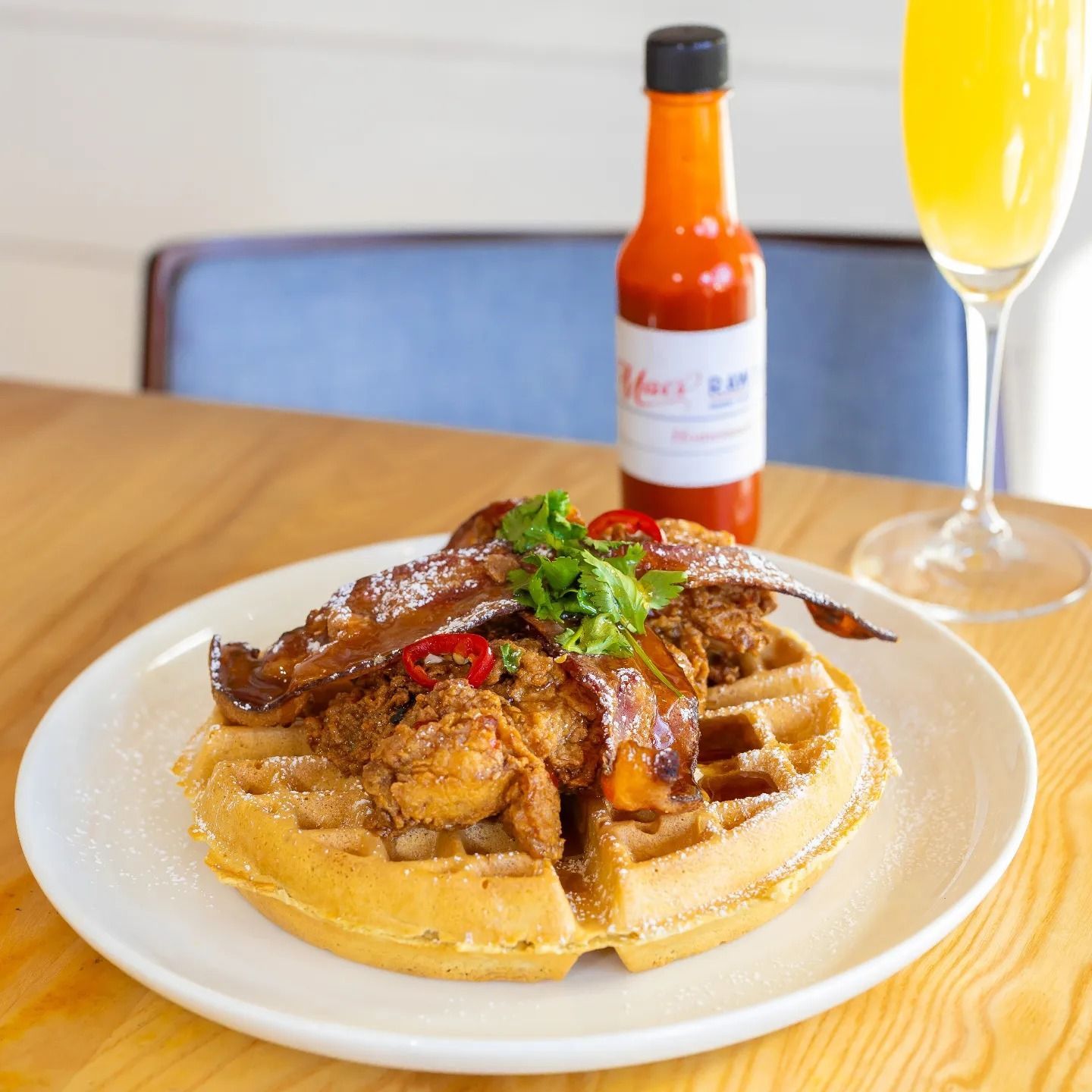 A plate of food with a bottle of hot sauce in the background