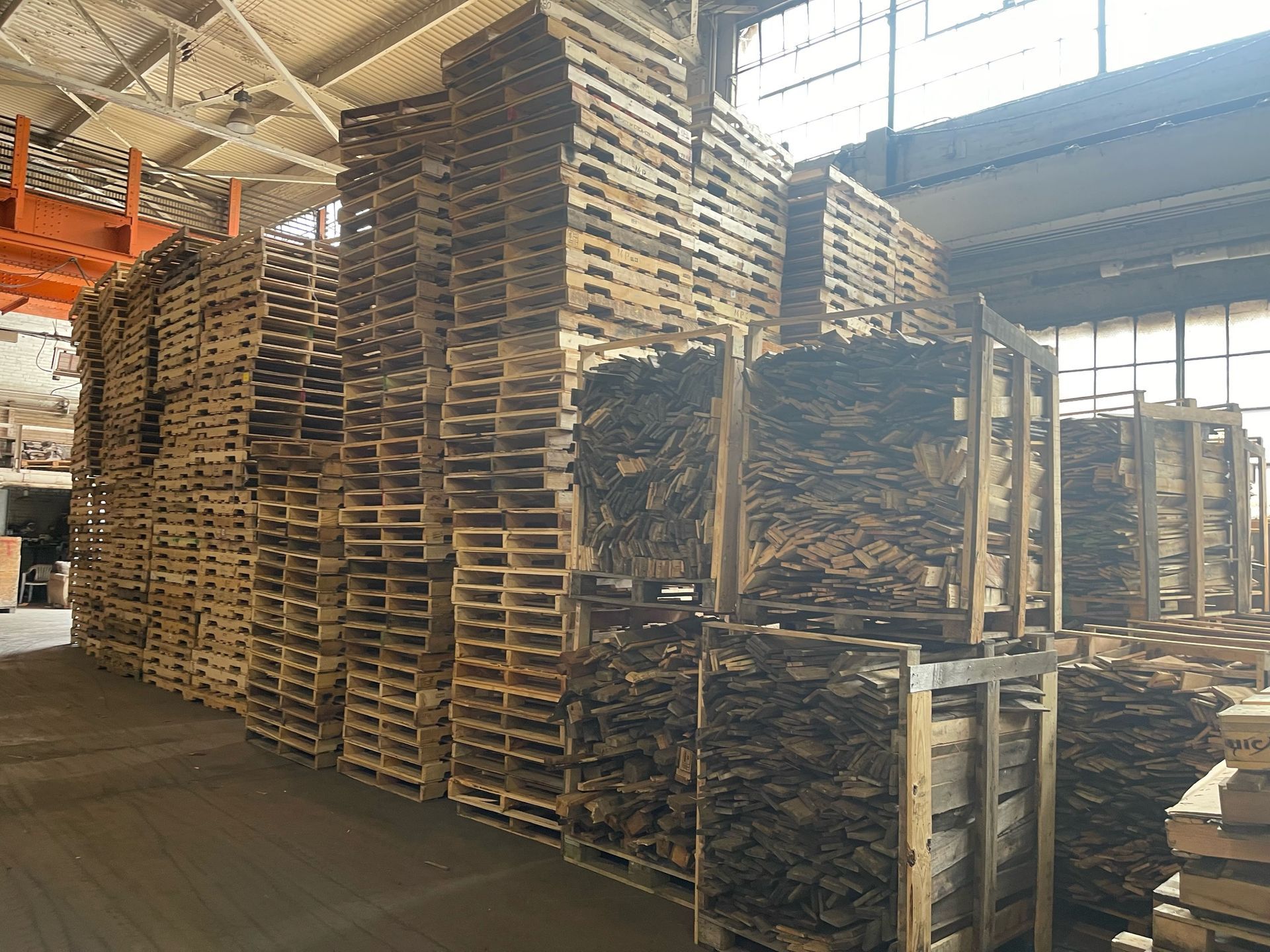 Stacks of wooden pallets inside a warehouse, a storage area.