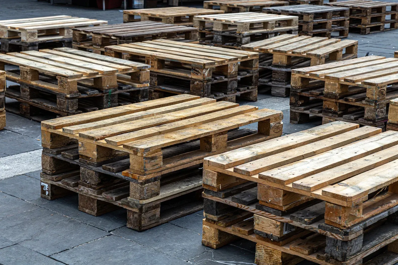 Wooden shipping pallets stacked on a gray concrete surface.