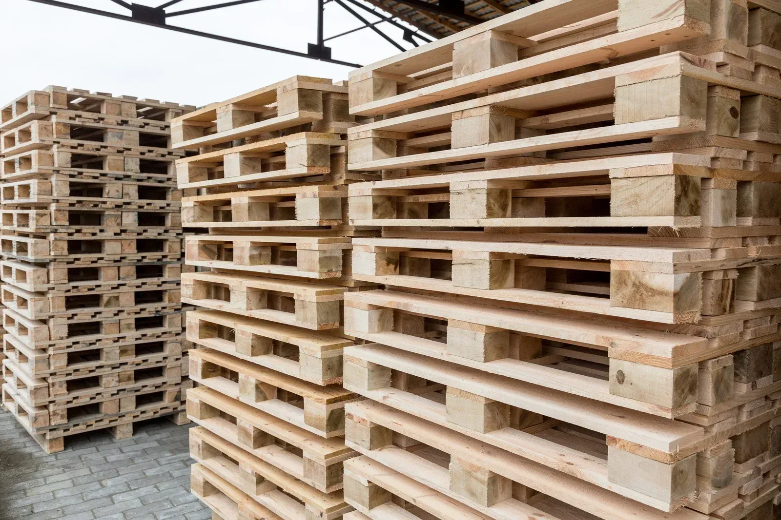 Stacks of wooden pallets in a warehouse setting.