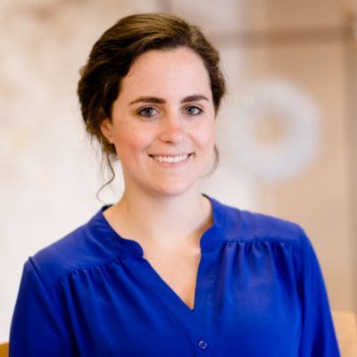 Woman with dark hair, wearing a blue shirt, smiling, looking at the camera.