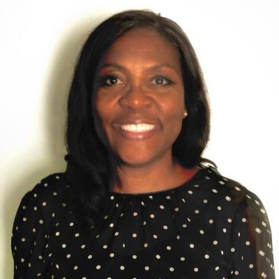 Woman in black polka dot top smiles at the camera.