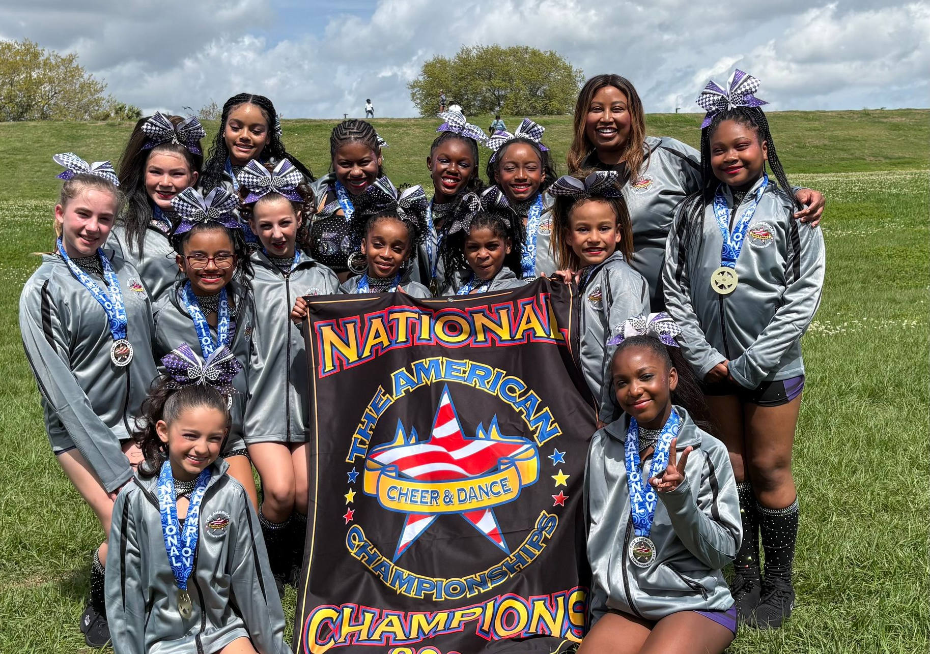 A cheerleading team in matching gray jackets holds a 
