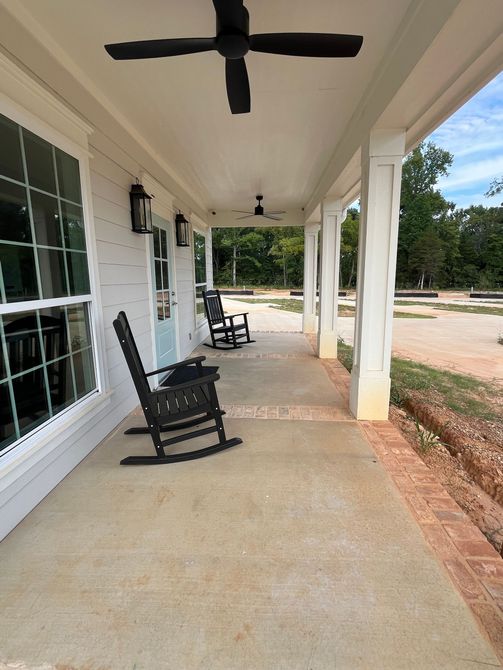 A porch with rocking chairs and a ceiling fan