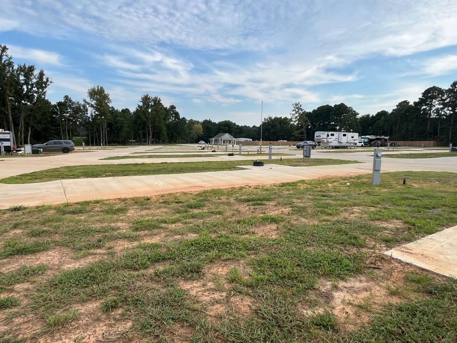 A rv park with a lot of grass and trees in the background.