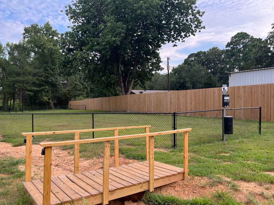 There is a wooden bridge in the middle of a field.