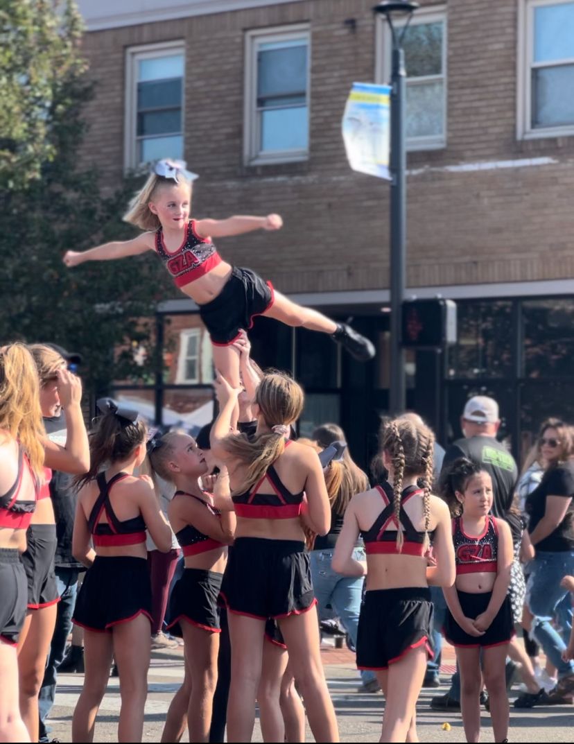 A cheerleader is being lifted in the air by another cheerleader