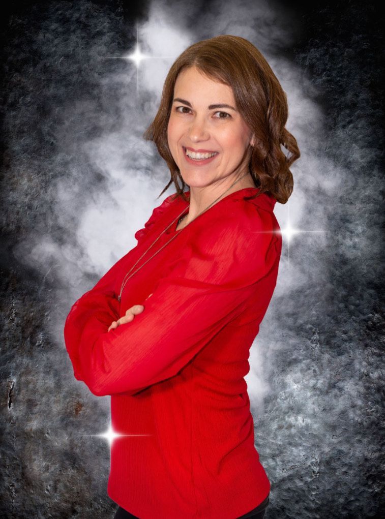 A woman in a red shirt is posing for a picture with her arms crossed.