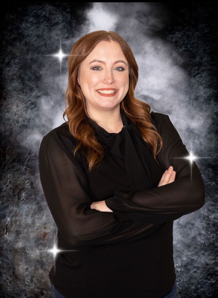 A woman in a black shirt is posing for a picture with her arms crossed.