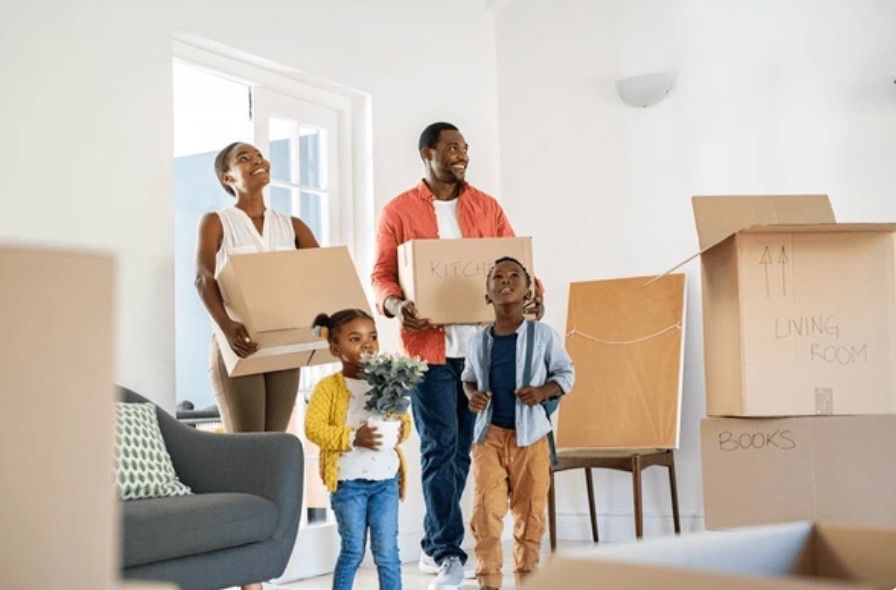 A family carrying moving boxes into their new home.