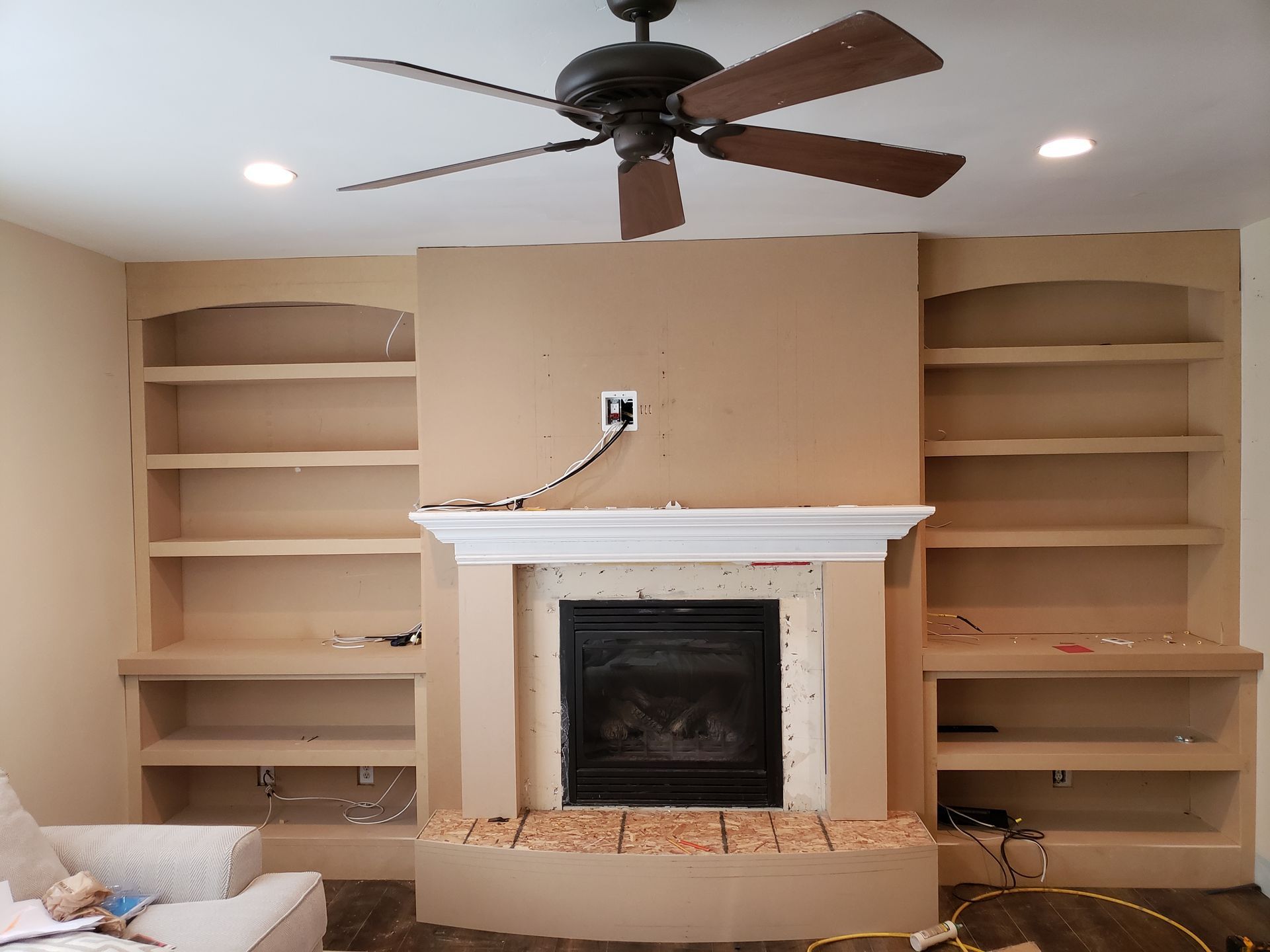 A living room with a fireplace and a ceiling fan