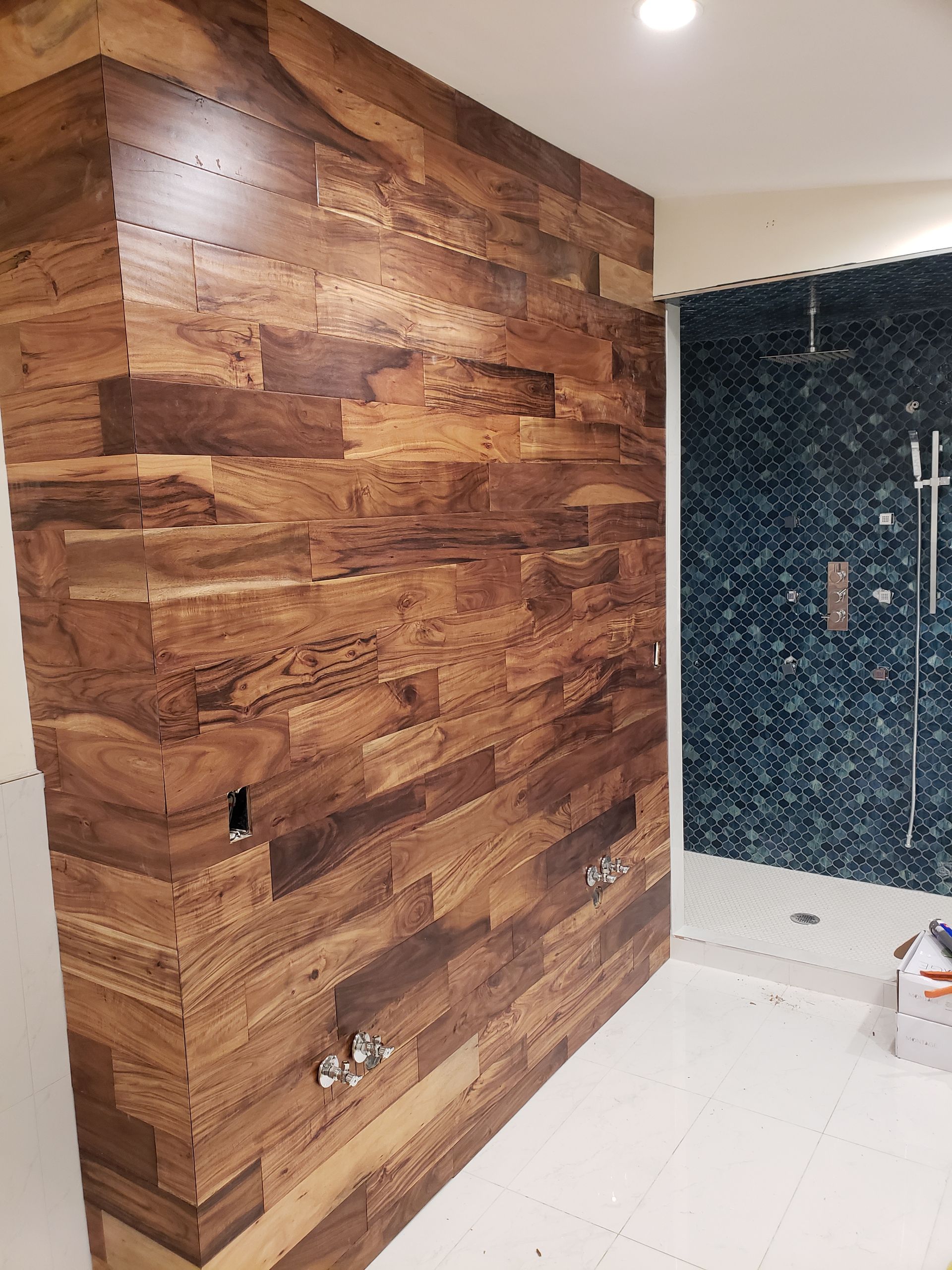 A bathroom with a wooden wall and a walk in shower.