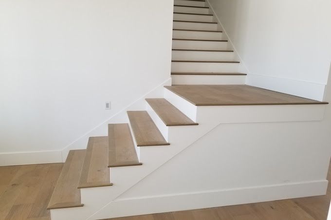 A white staircase with wooden steps in a room.