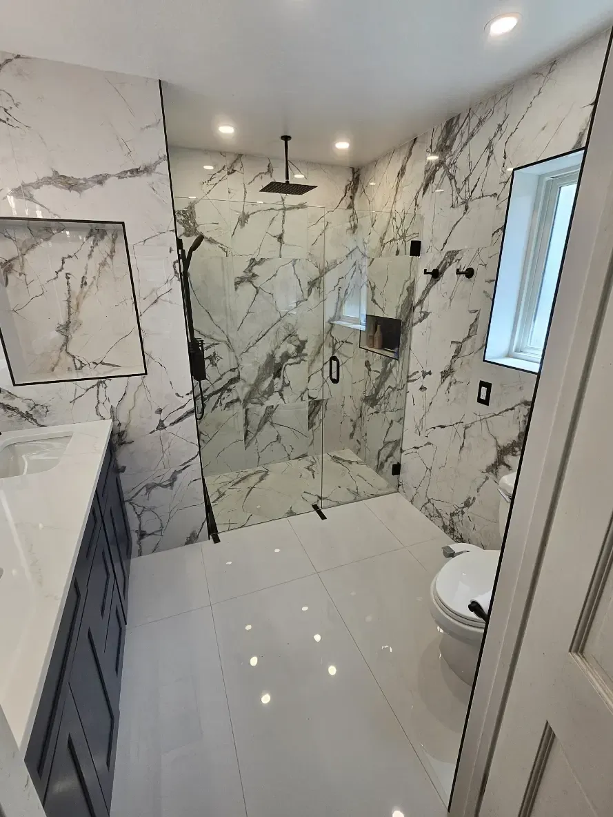 A bathroom with marble walls and a walk in shower.