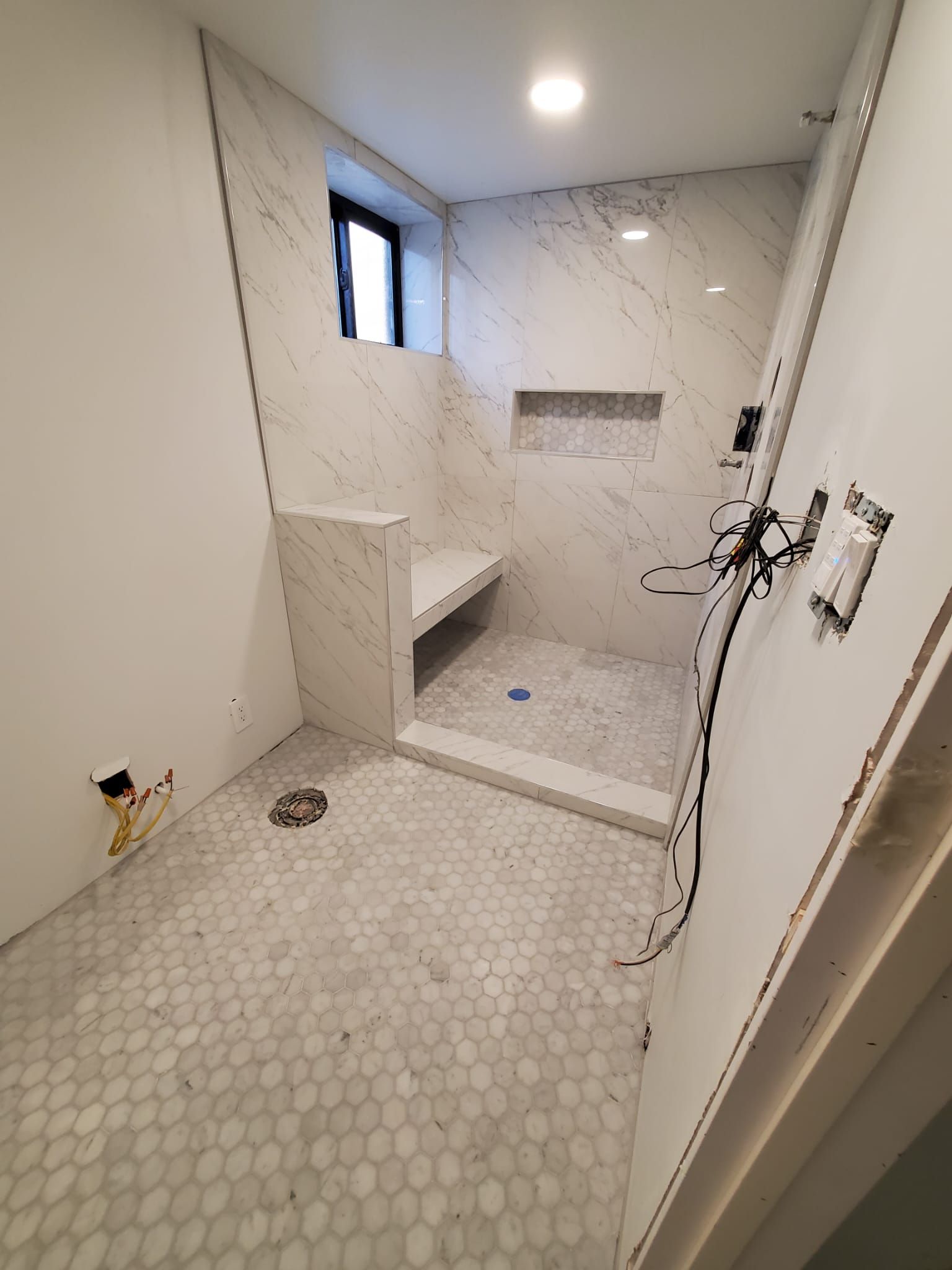 A bathroom with a walk in shower and a window.