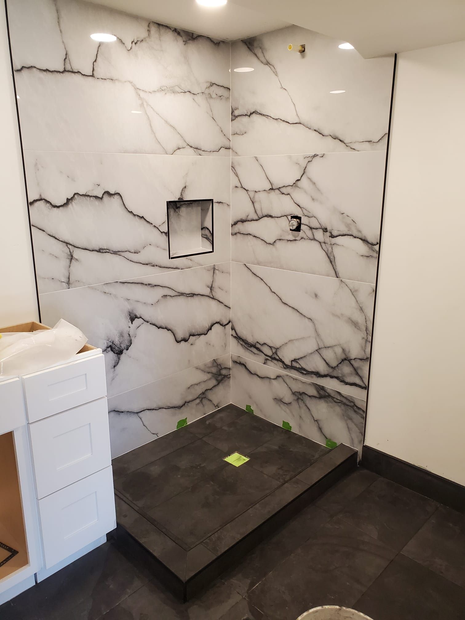 A bathroom with a walk in shower and a marble wall
