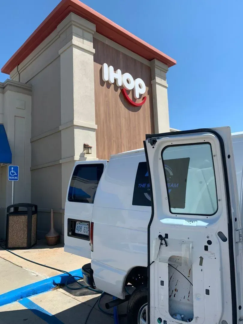 A white van is parked in front of an ihop restaurant