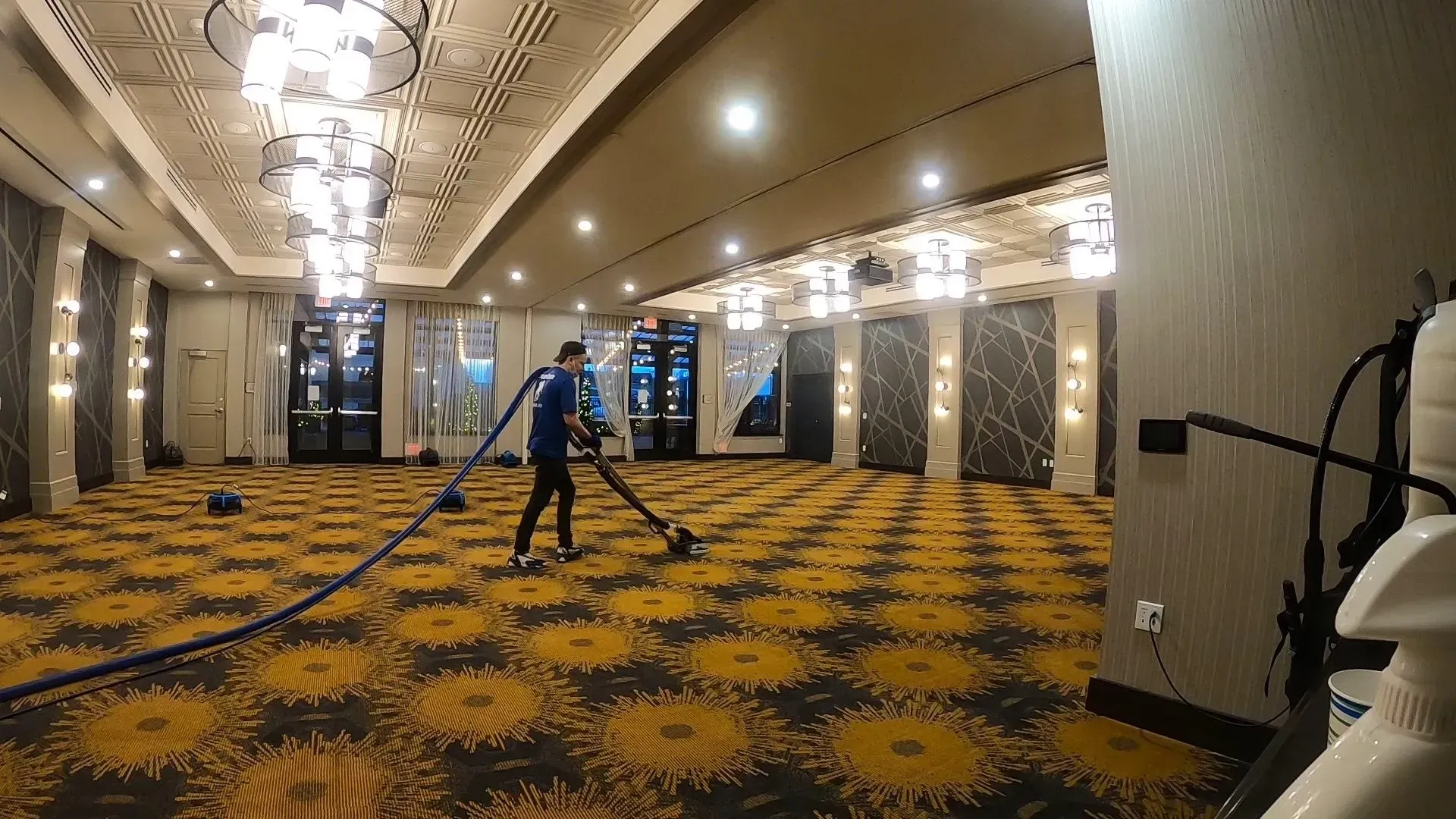 A man is cleaning a large room with a vacuum cleaner.