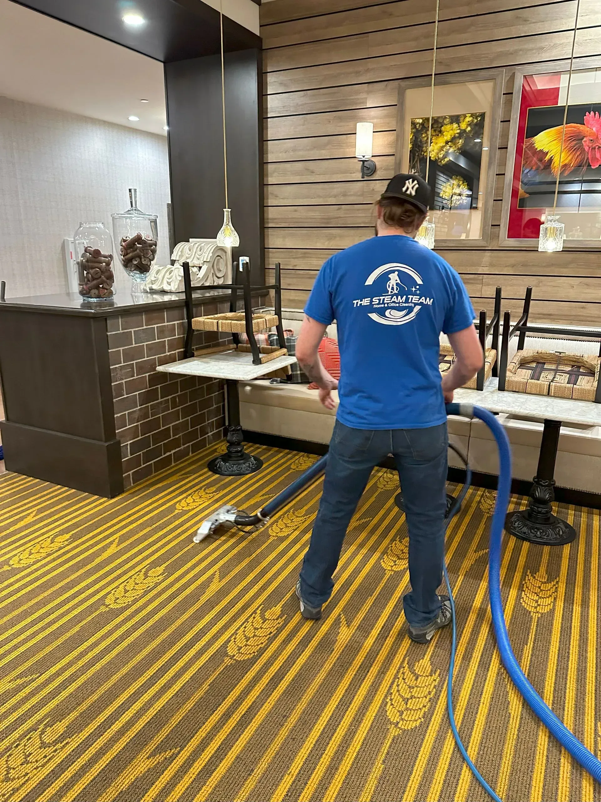 A man is cleaning the floor of a restaurant with a vacuum cleaner.
