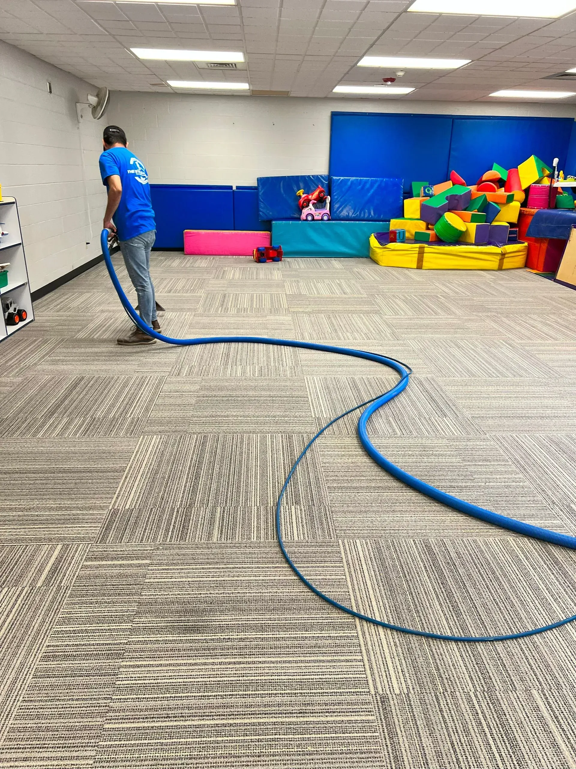 A man is cleaning the floor of a room with a vacuum cleaner.