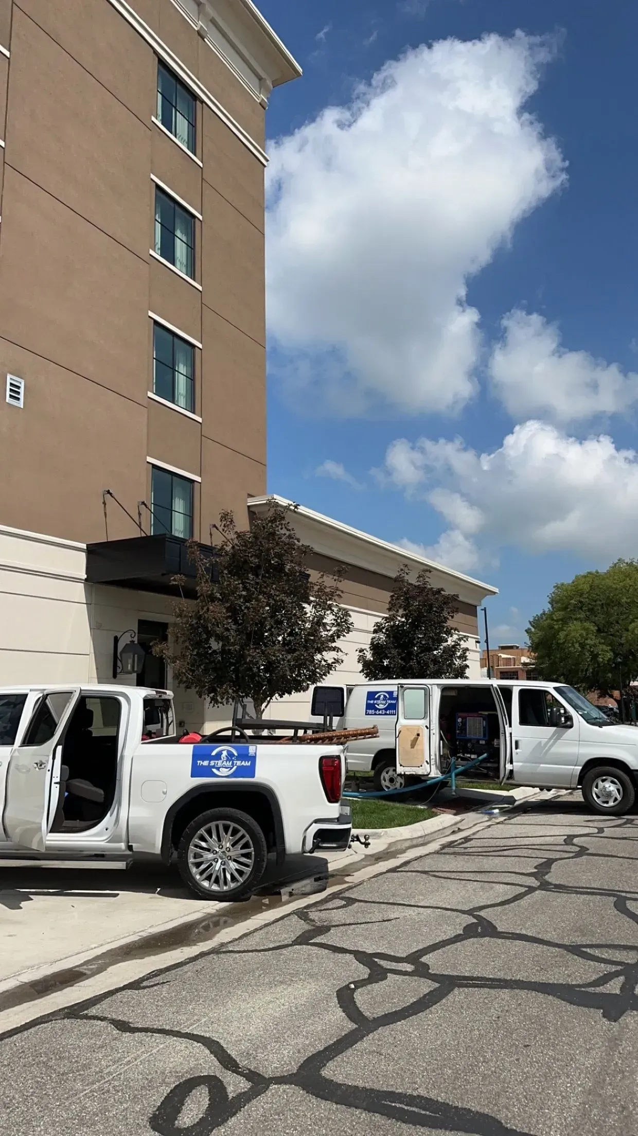 Two trucks and a van are parked in front of a building.